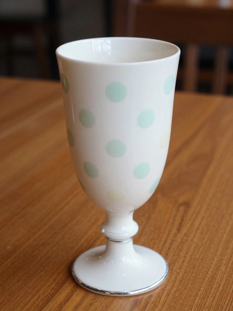 White ceramic goblet with mint green and yellow polka dots on wooden table