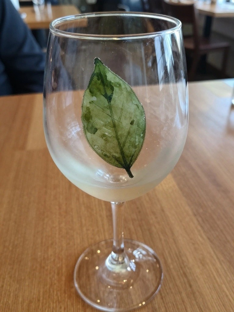 Stemmed wine glass with green leaf design on wooden restaurant table