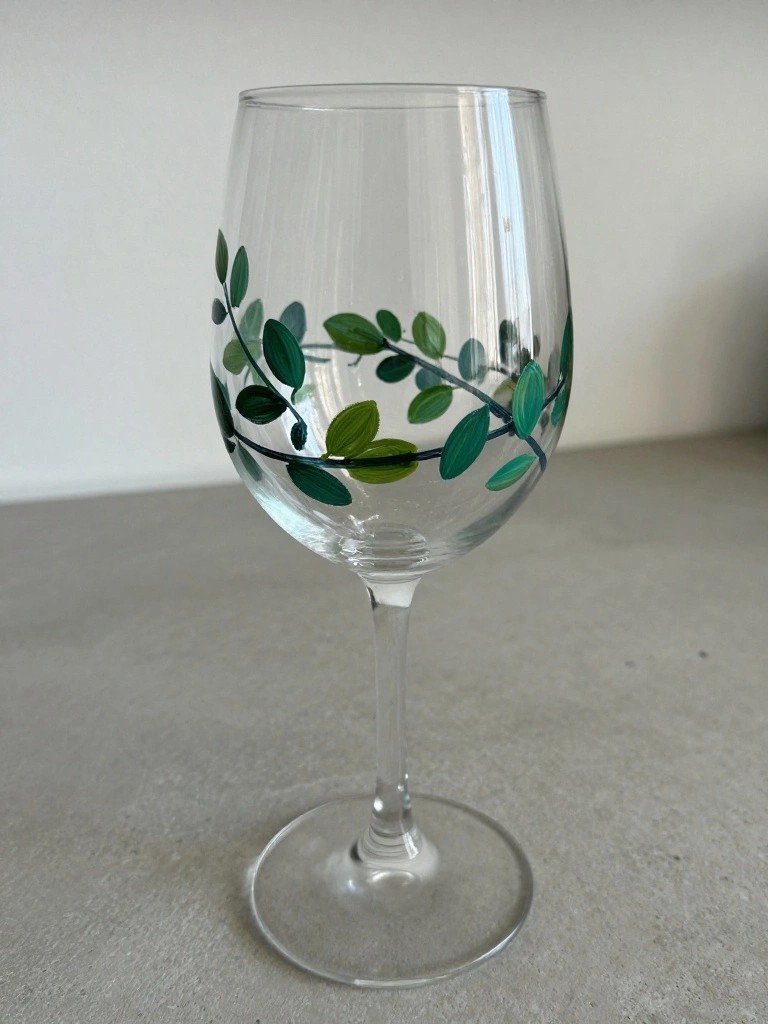 Clear wine glass with painted green leaf vine wrapping around bowl