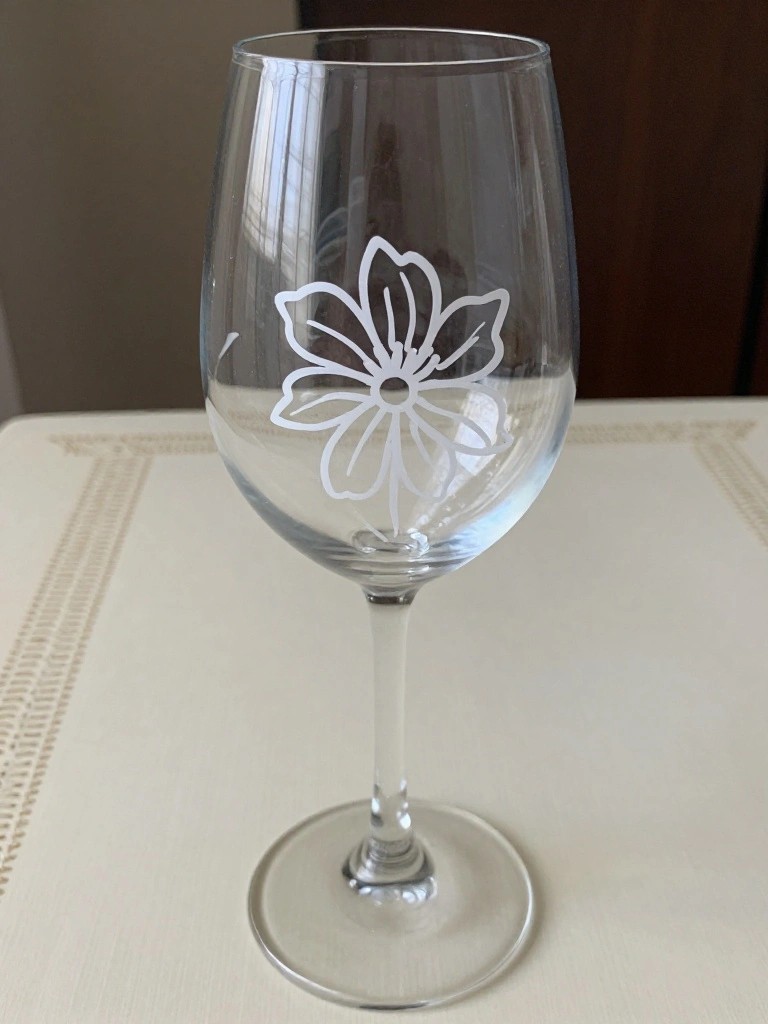 Clear wine glass with white floral etching on white tablecloth