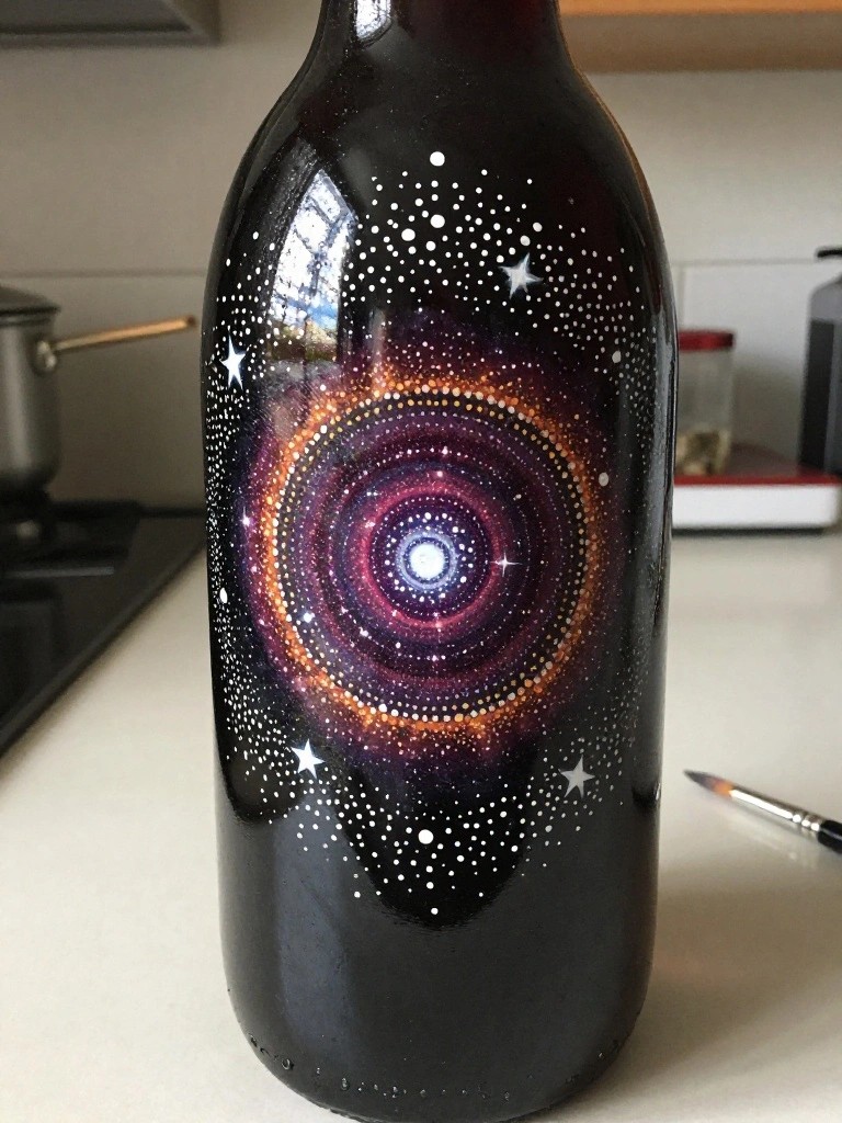 Black bottle painted with swirling purple-orange galaxy and white star dots