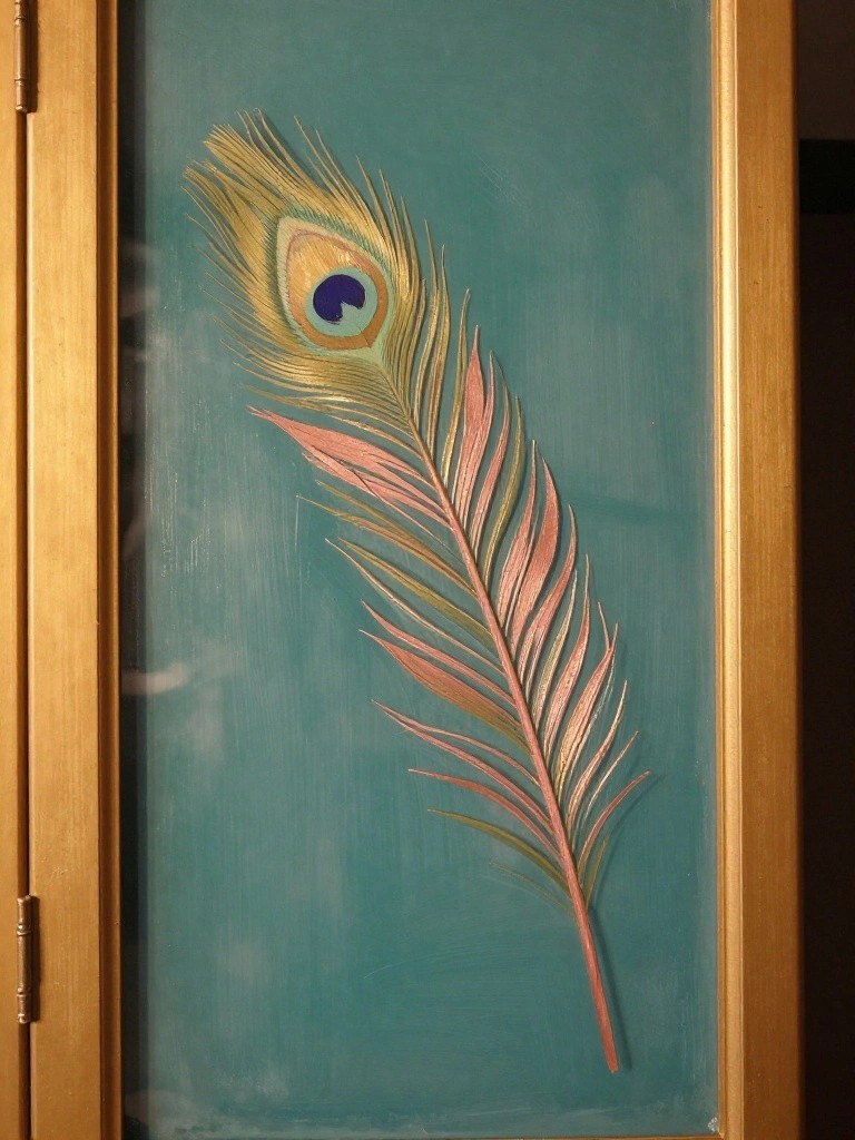 Colorful peacock feather with blue eye on textured teal background in wooden frame