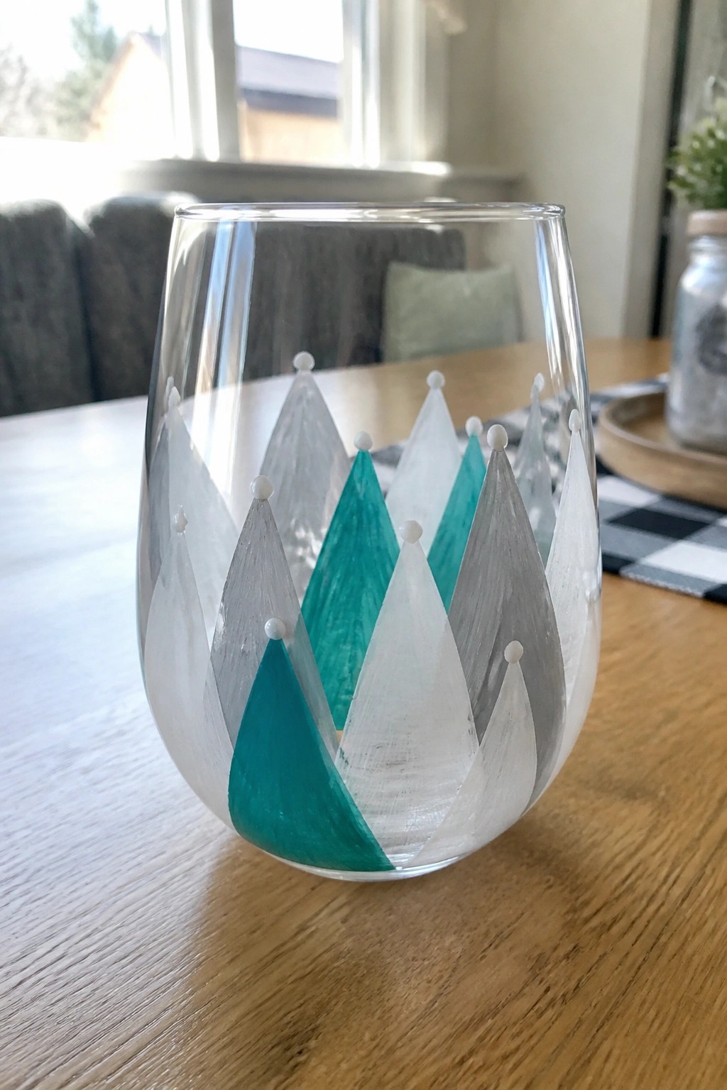 Stemless glass with teal gray and white triangular mountain designs on wood table
