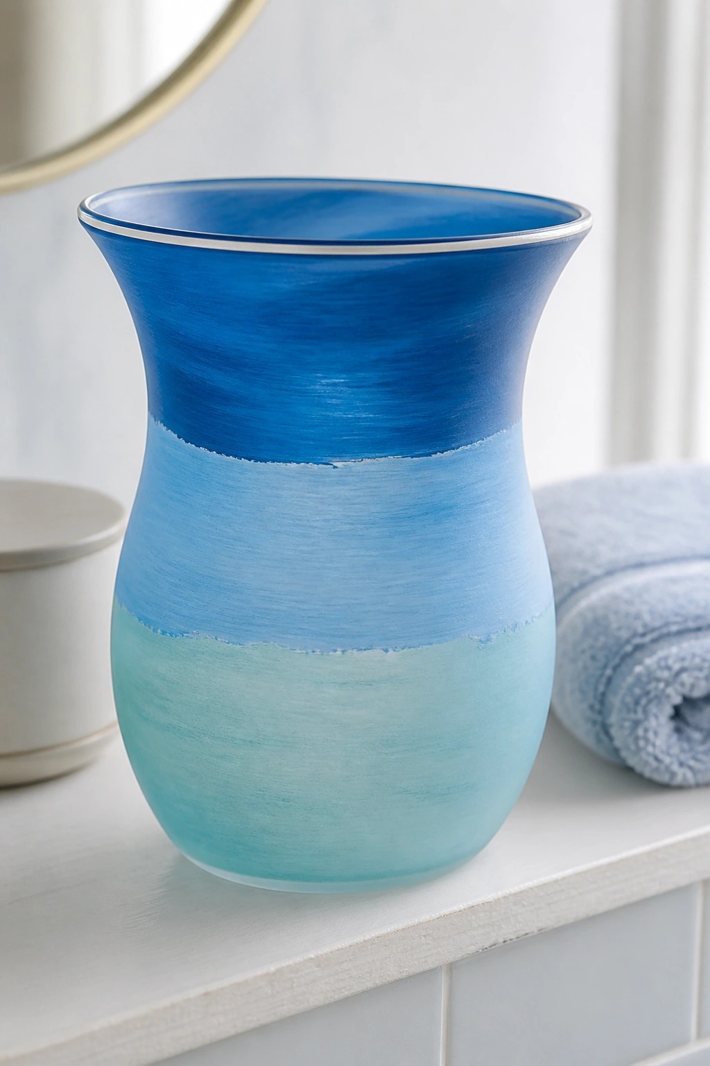 Blue gradient ceramic vase with silver rim on white bathroom counter