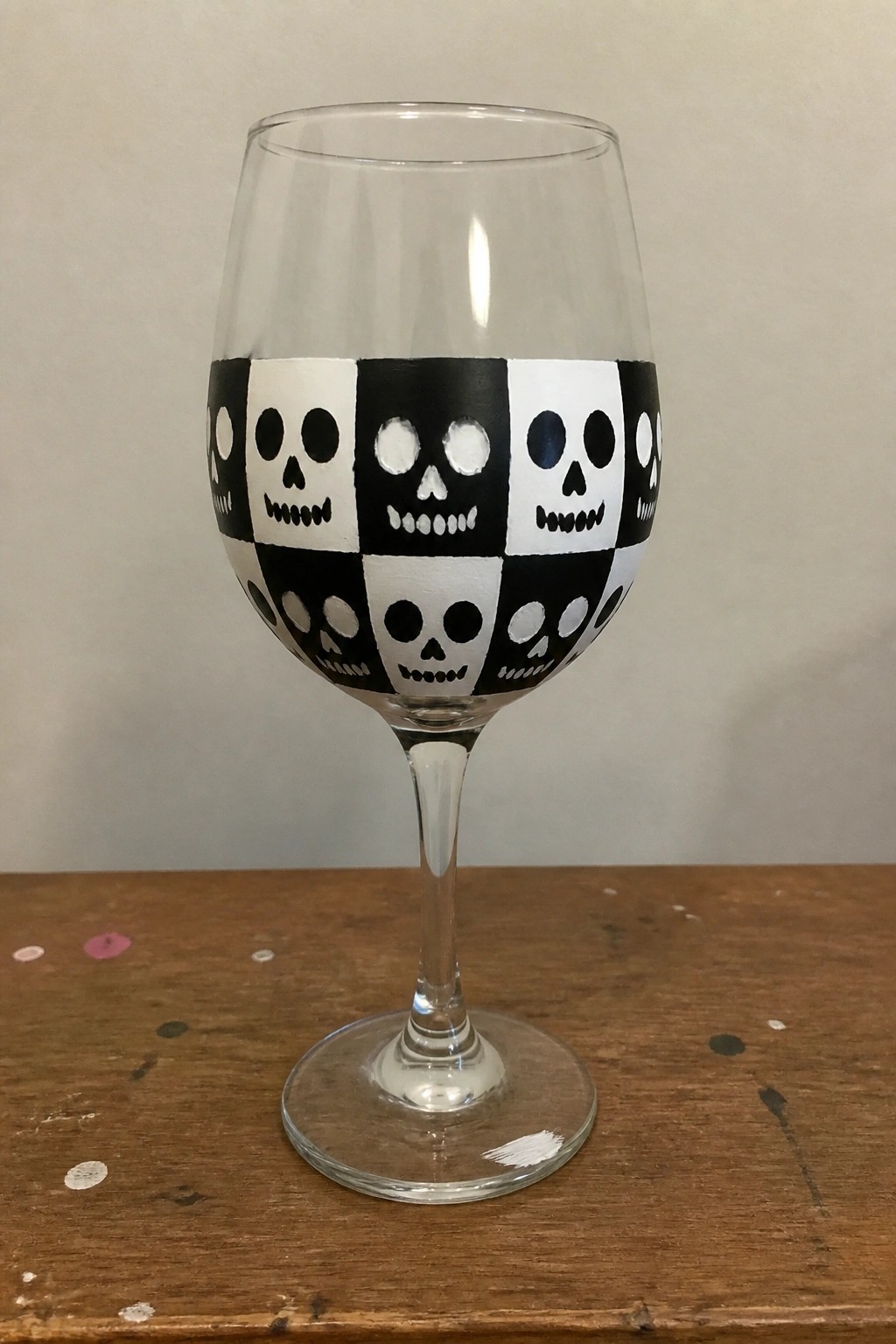 Wine glass with black-and-white checkered skull pattern on wooden table