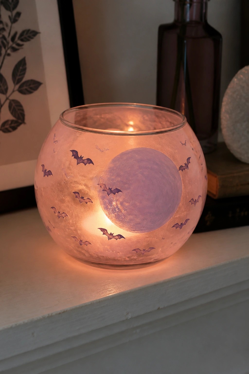 Glowing frosted glass bowl with purple bats circling a painted moon on shelf