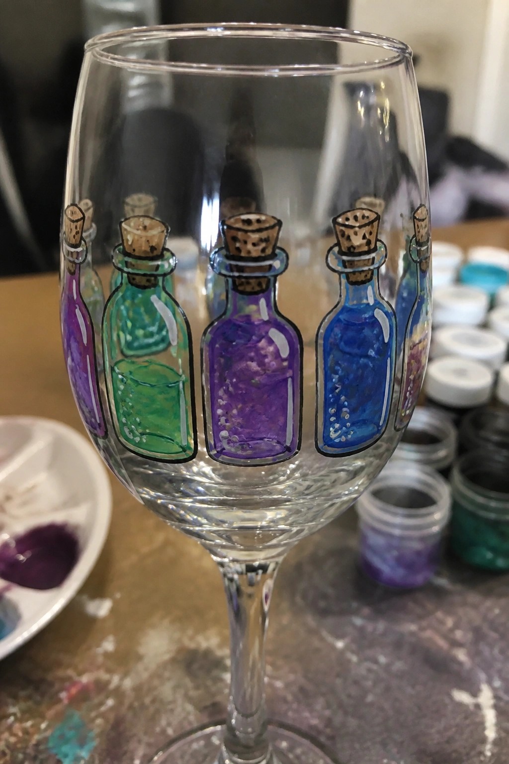 Wine glass hand-painted with five colorful corked potion bottles containing bubbles