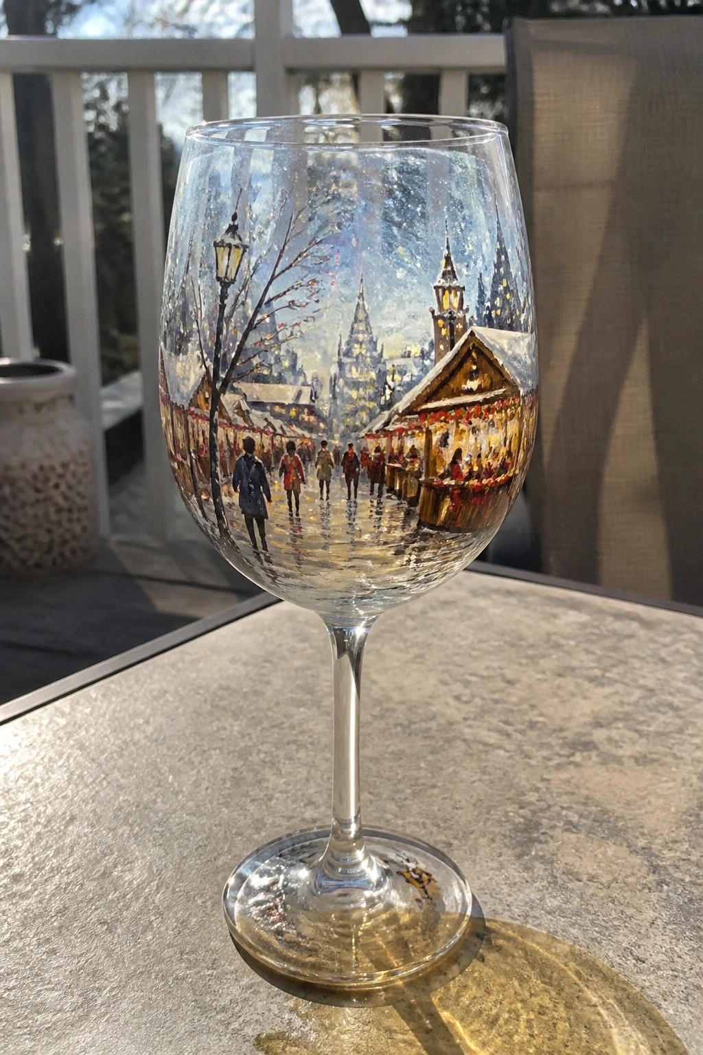 Painted wine glass with snowy market scene, people, stalls, and glowing spires