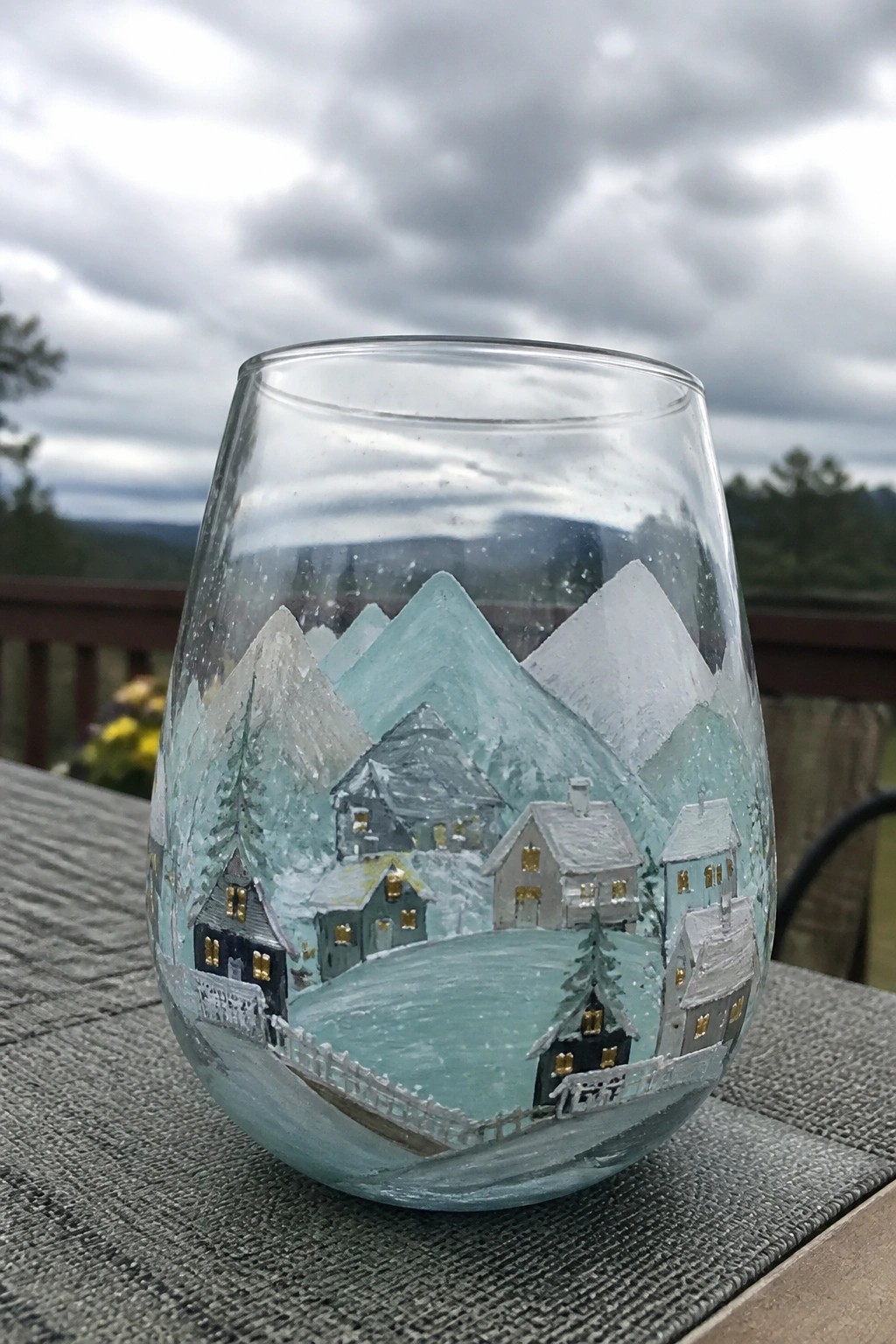 Stemless wine glass hand-painted with snowy village, mountains, and glowing windows.