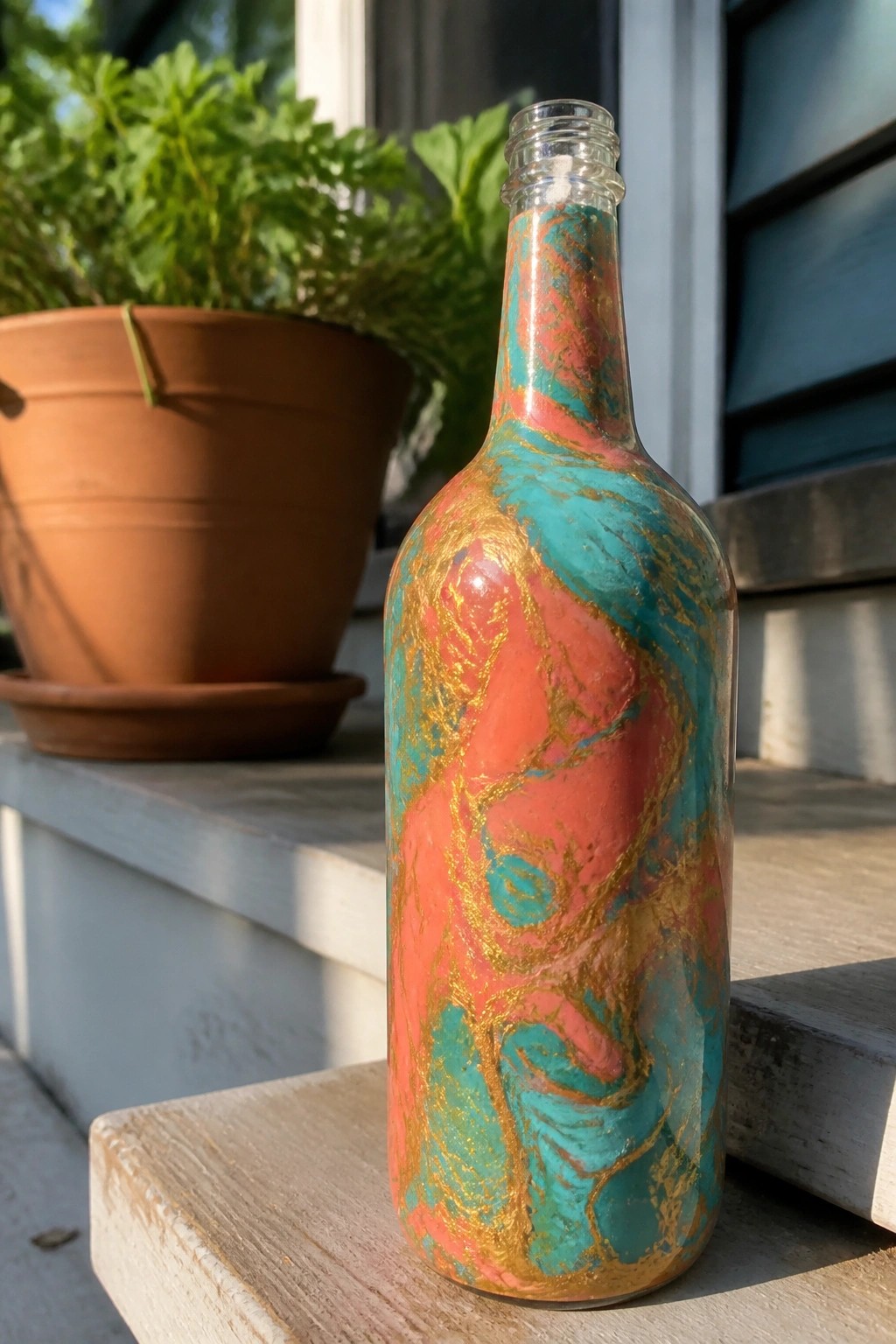 Marbled glass bottle in coral, turquoise, and gold on wooden steps
