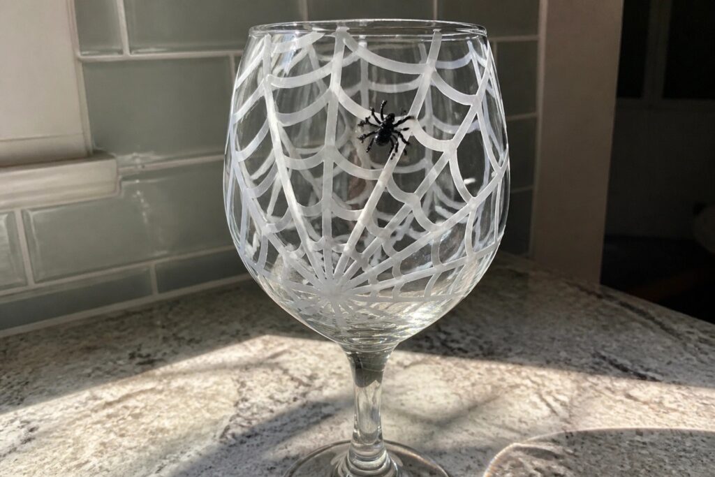 20 Creepy Spider Web Wine Glass Ideas Using Wraparound Web Designs Wine glass with white spiderweb design and black spider on kitchen counter