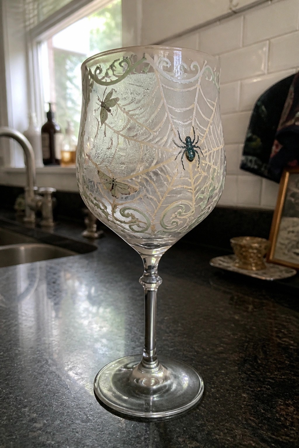 Ornate etched glass with spiderweb, spider, and moths on kitchen countertop