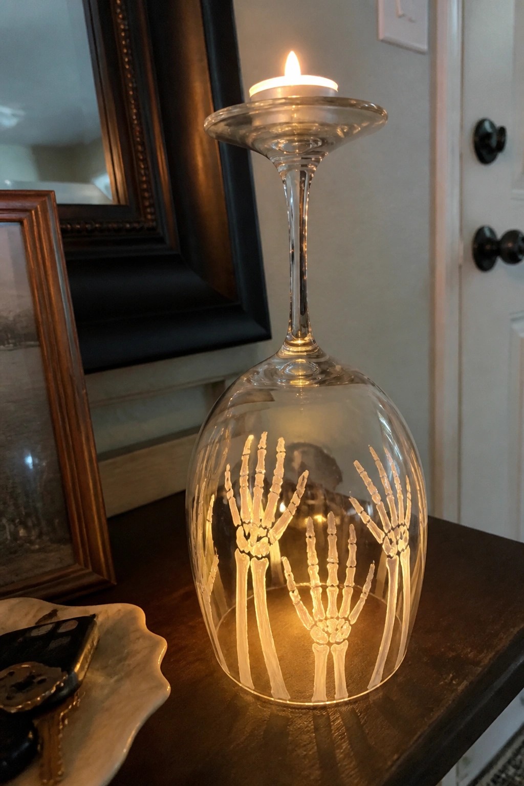 Illuminated wine glass etched with skeleton hands topped with a lit candle