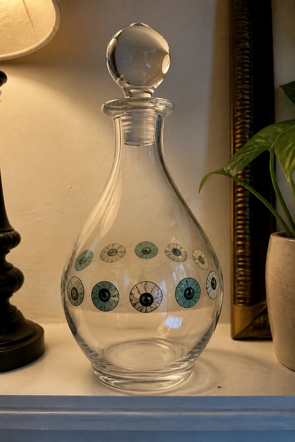 Clear glass decanter with colorful painted eyes and spherical stopper