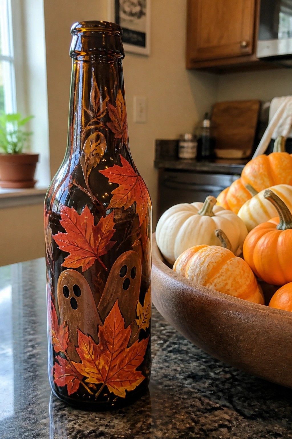 Brown bottle painted with autumn leaves and ghosts beside bowl of pumpkins