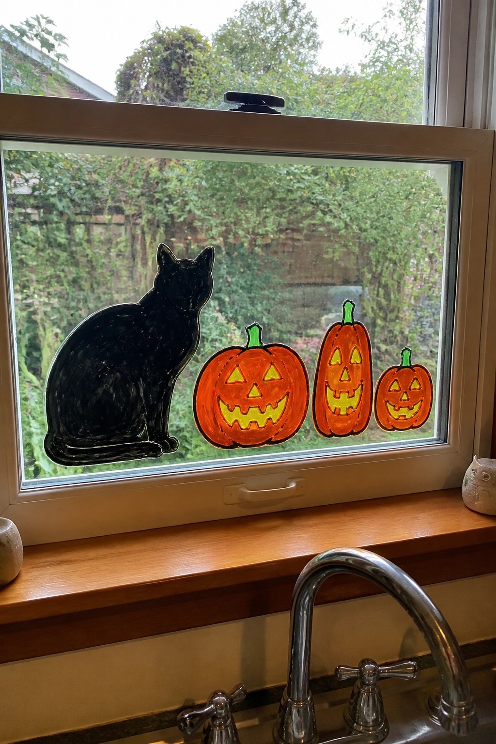 Black cat and three orange jack-o'-lantern decals on kitchen window