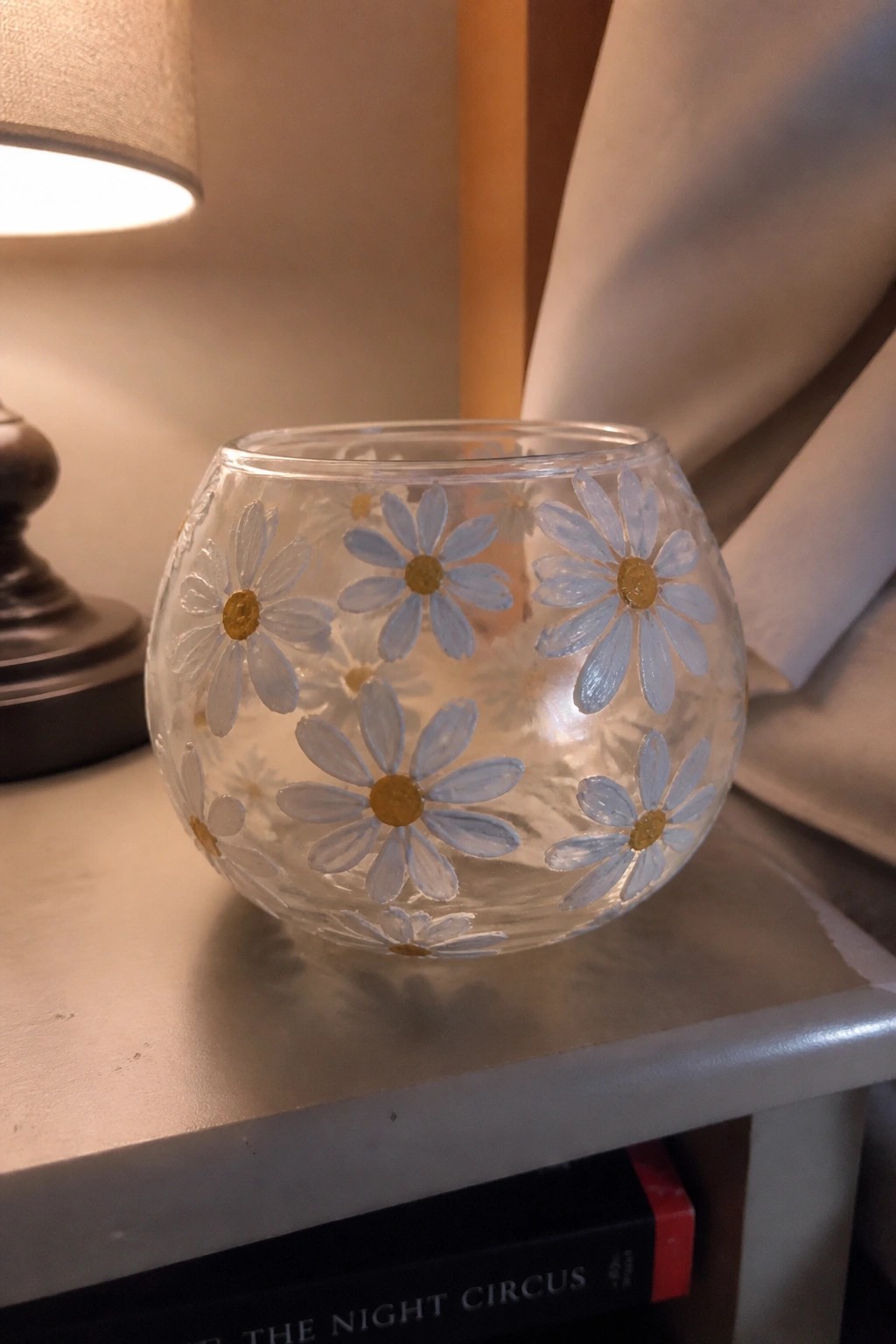 Glass bowl painted with light blue daisies and gold centers on a table
