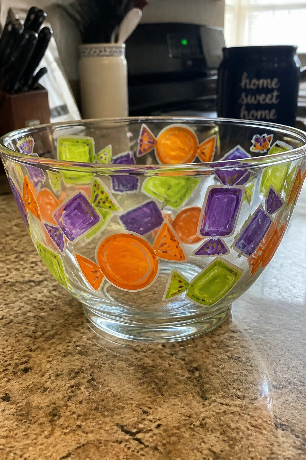 Glass bowl with colorful painted candy designs on speckled kitchen countertop