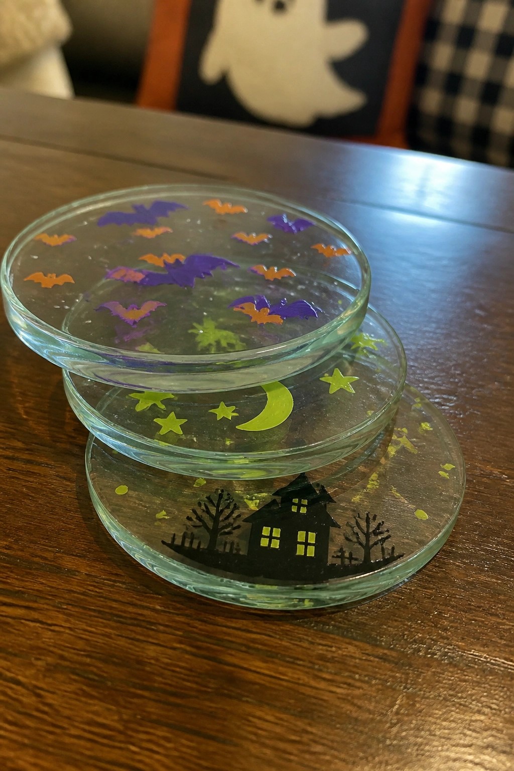 Stacked glass coasters with purple bats, green stars, yellow moon, and haunted house.
