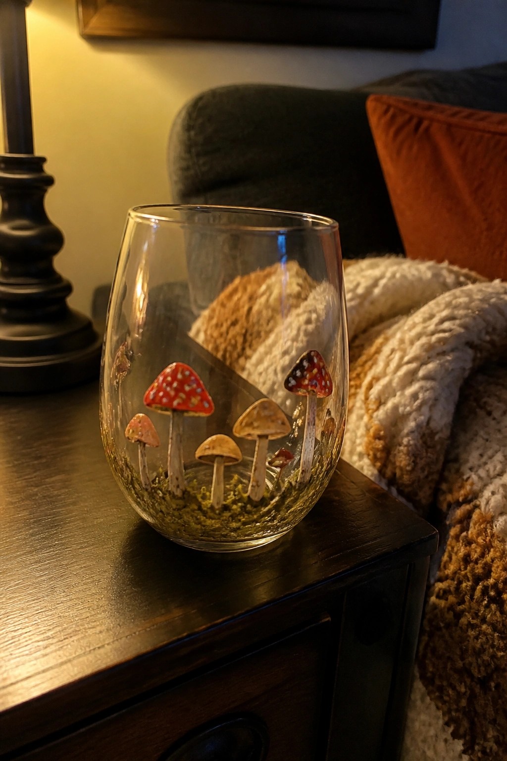 Stemless glass with red and brown mushroom illustrations plus green moss on wooden table