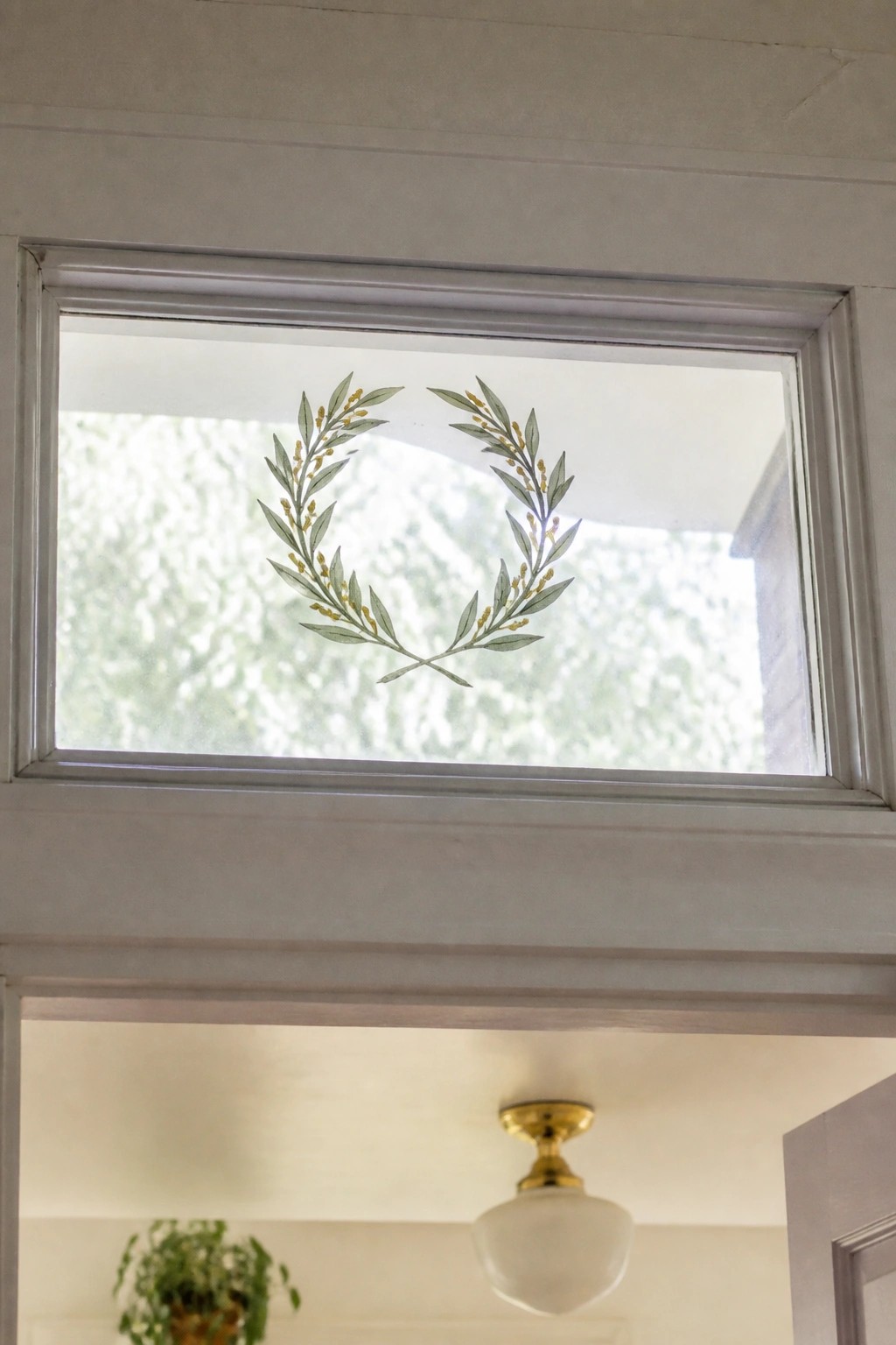 Transom window with green leaf and berry wreath decal above doorway