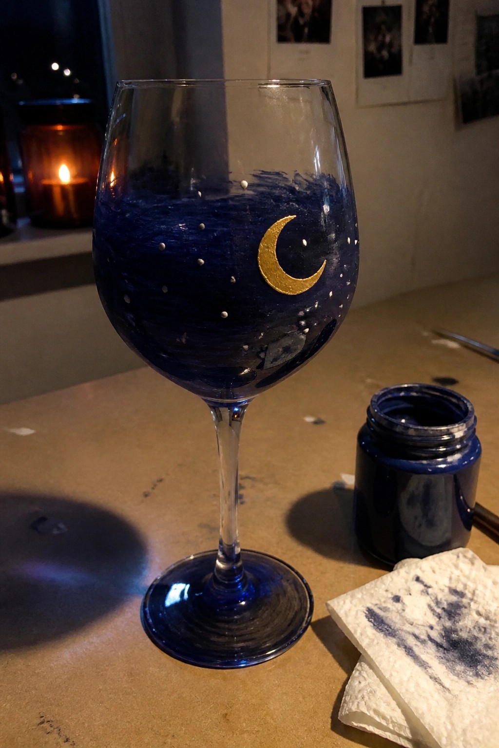 Blue painted wine glass with gold crescent moon and stars beside paint jar