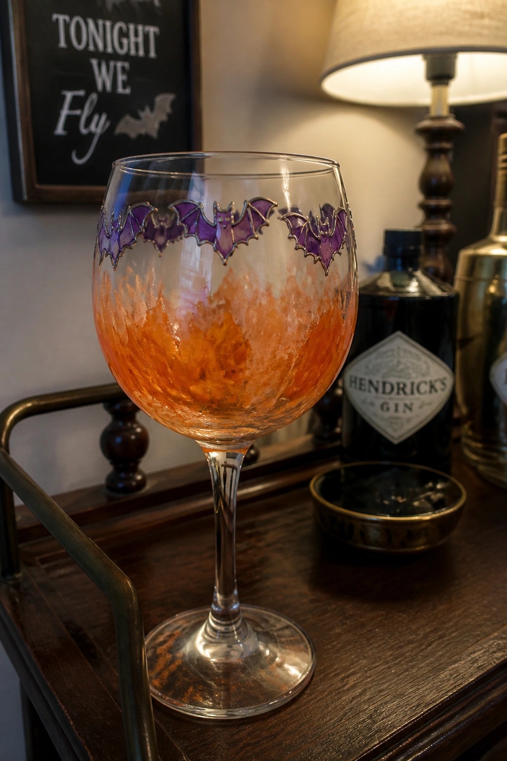 Wine glass with purple bat rim holding orange textured cocktail on wooden tray