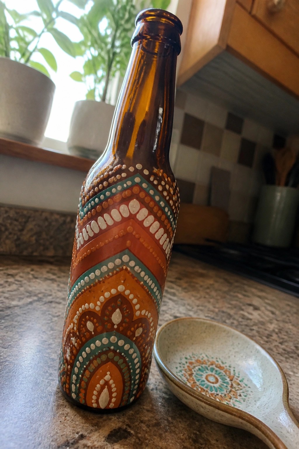 Painted brown bottle with colorful dot patterns beside matching ceramic spoon rest.