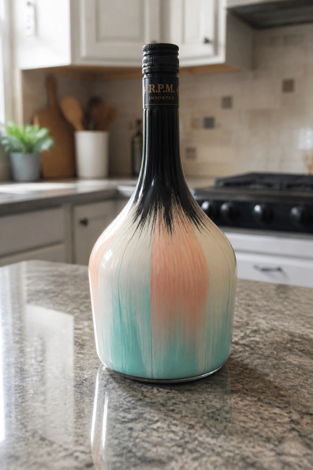 Artistically painted bottle with black, peach, and turquoise drips on marble counter