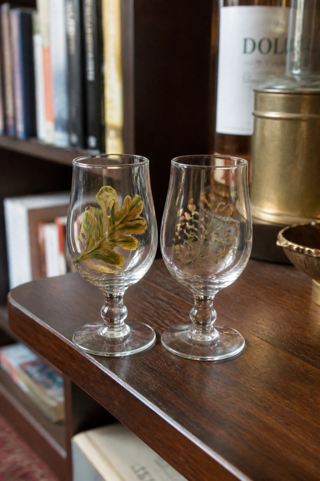 Two clear glass goblets with painted oak leaf and wildflowers on wooden table