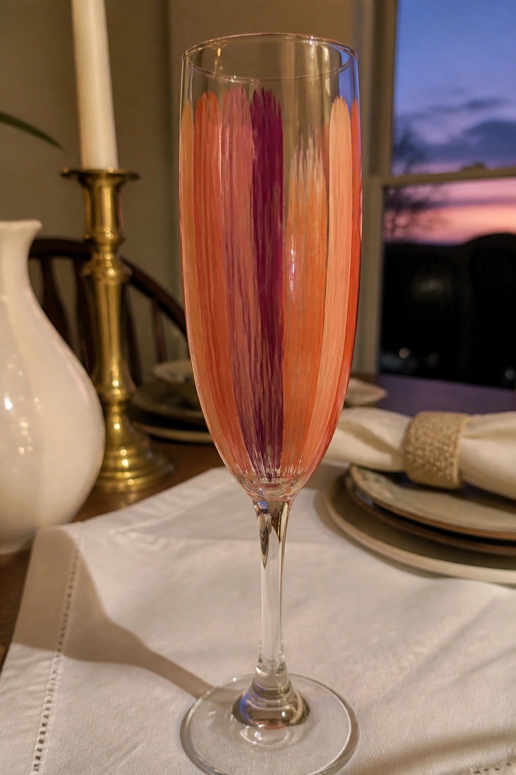 Colorful champagne flute with orange and purple brushstrokes on a set dining table