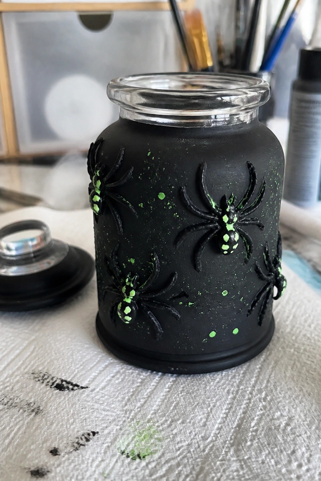 Black jar with raised black spiders featuring neon green accents and splatters.