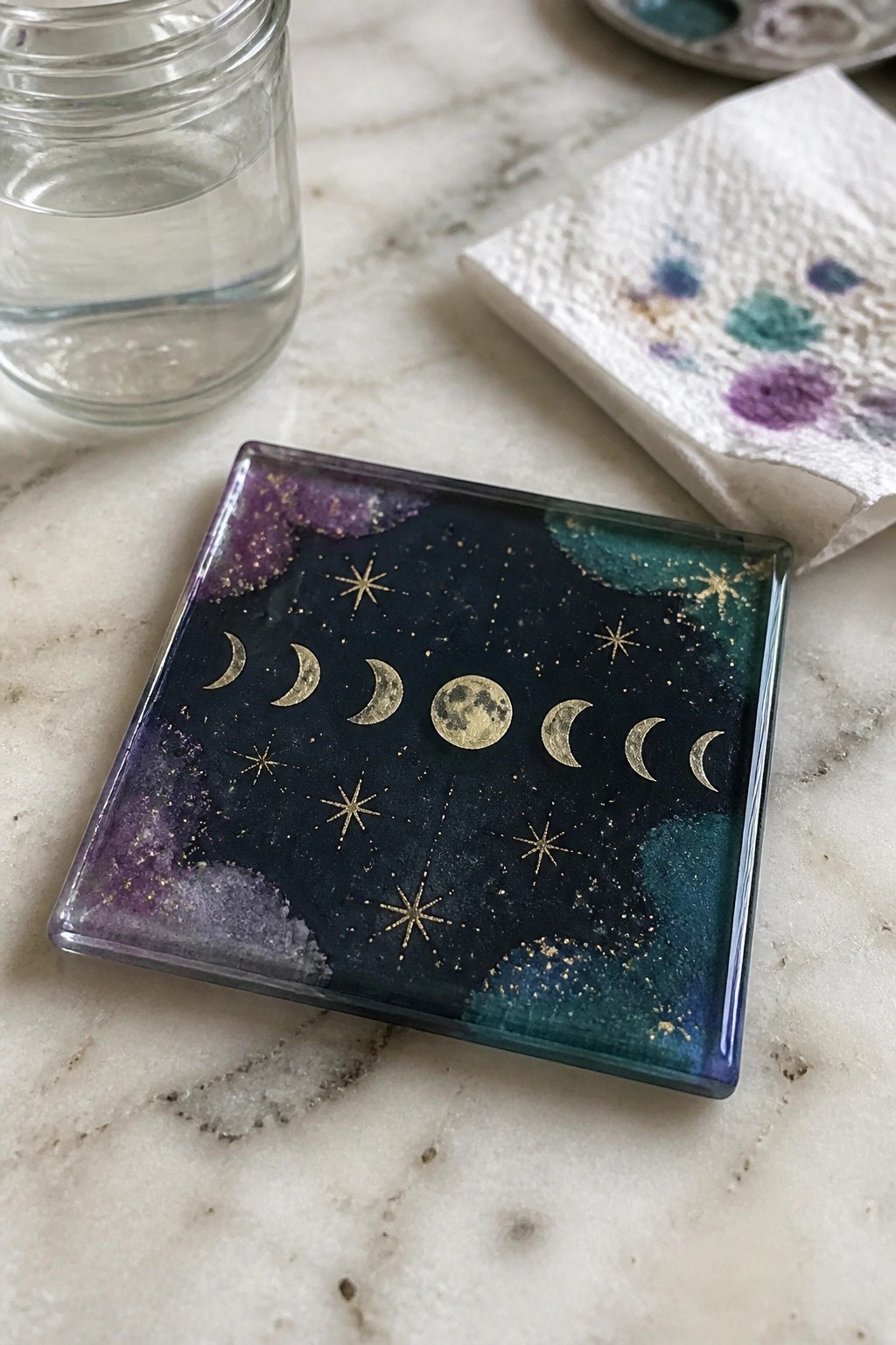 Resin coaster with gold moon phases and stars on glittery purple teal galaxy background