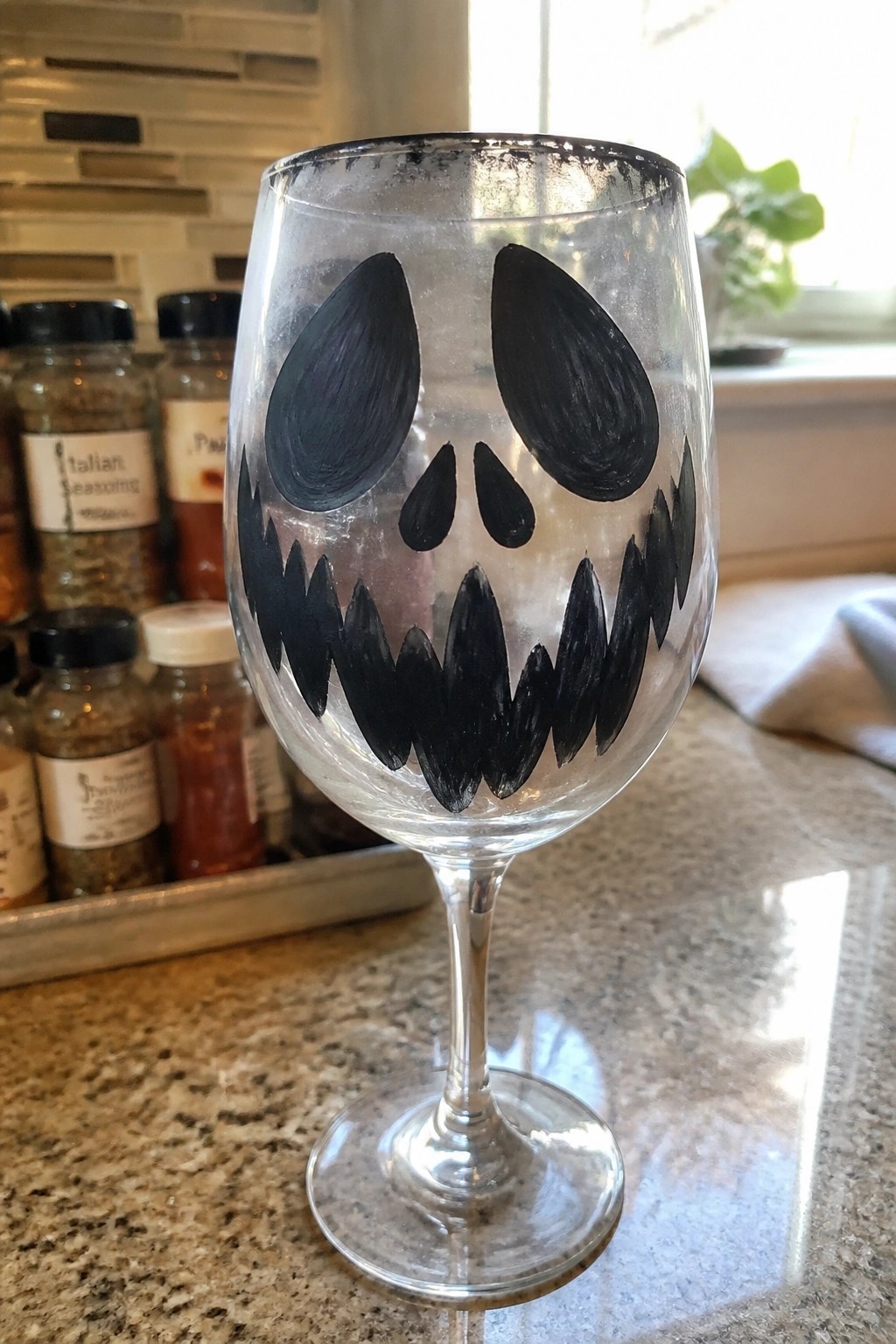 Wine glass with black jack-o'-lantern face on kitchen countertop