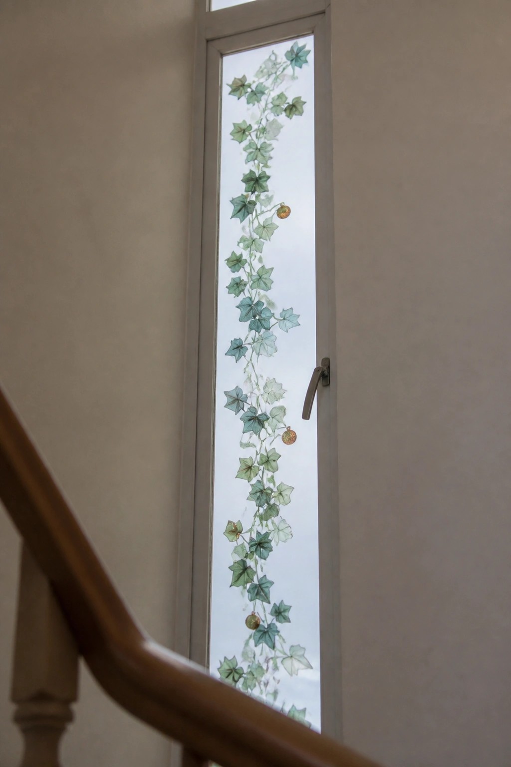 Narrow window with green ivy vine decal and gold ornaments near wooden railing