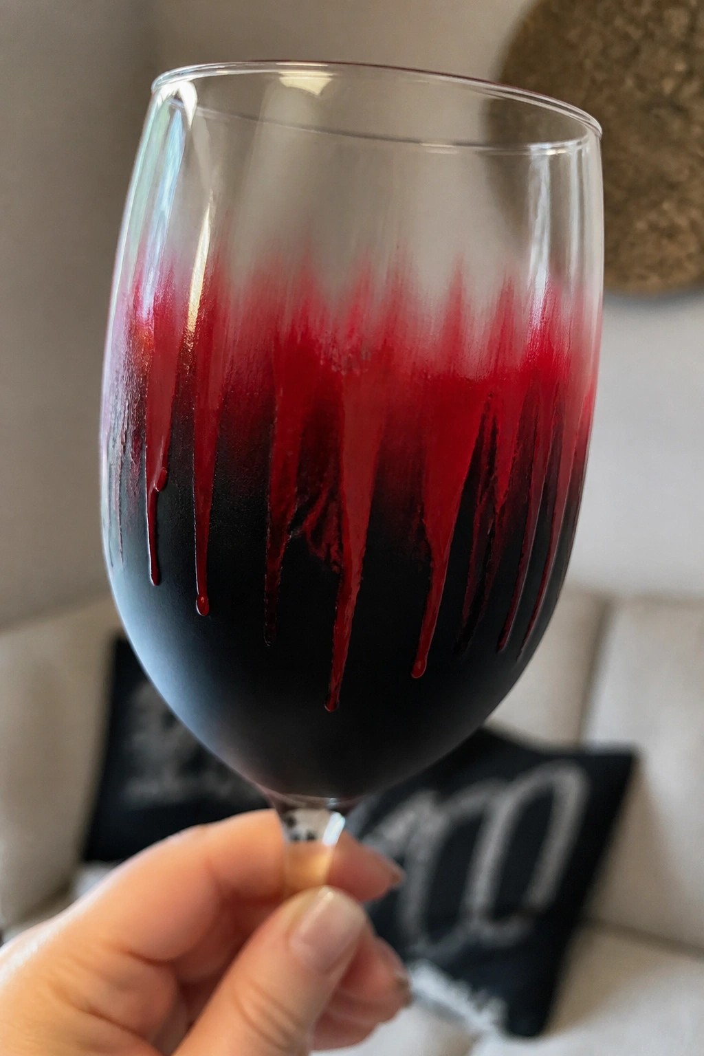 Hand holding wine glass with black base and red dripping design