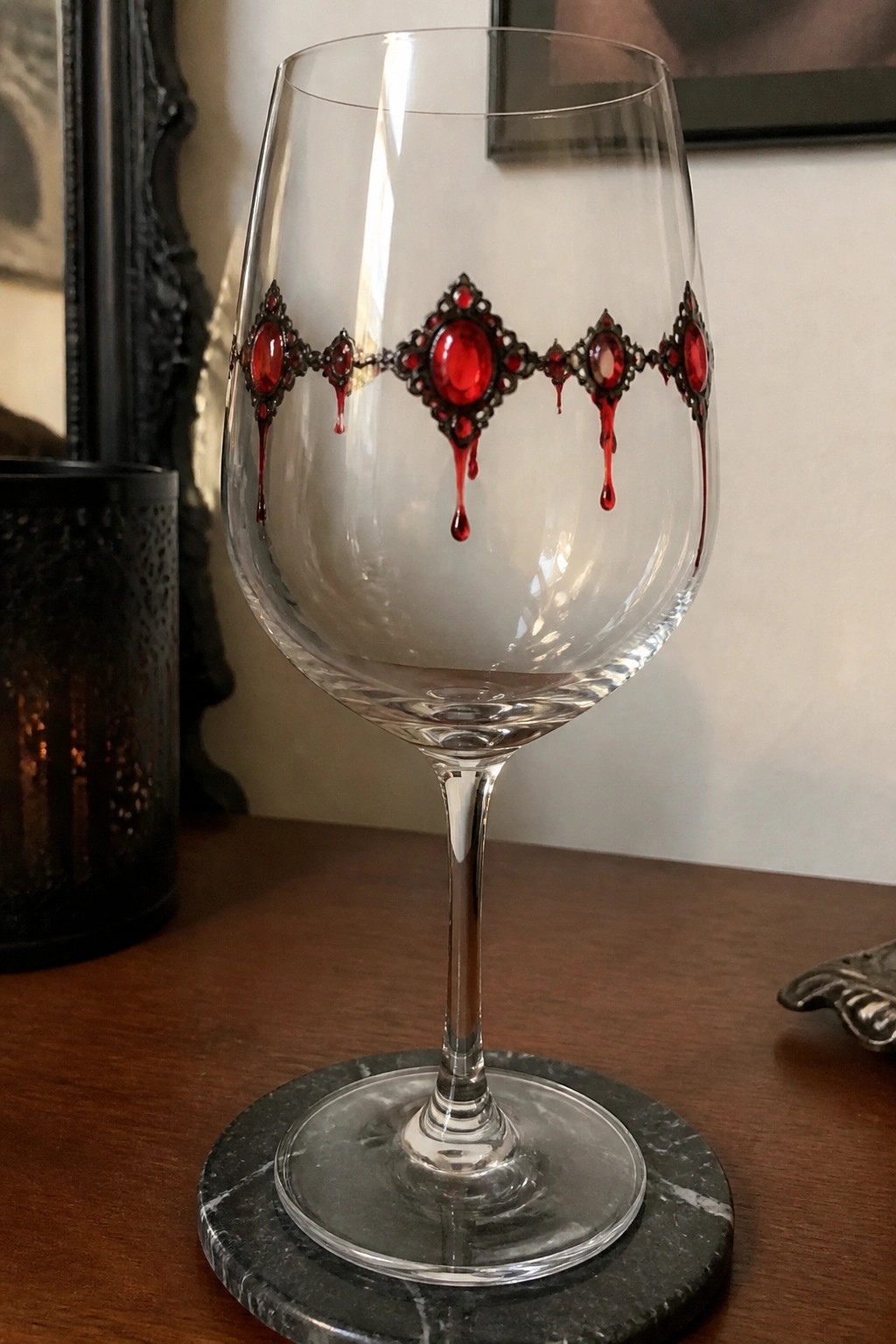 Ornate wine glass with red gemstones and blood-like drips on marble coaster.
