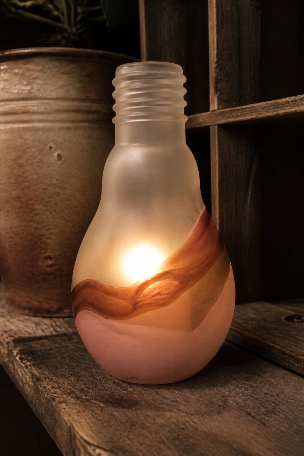 Frosted glowing light bulb lantern with swirling brown and pink patterns on wood