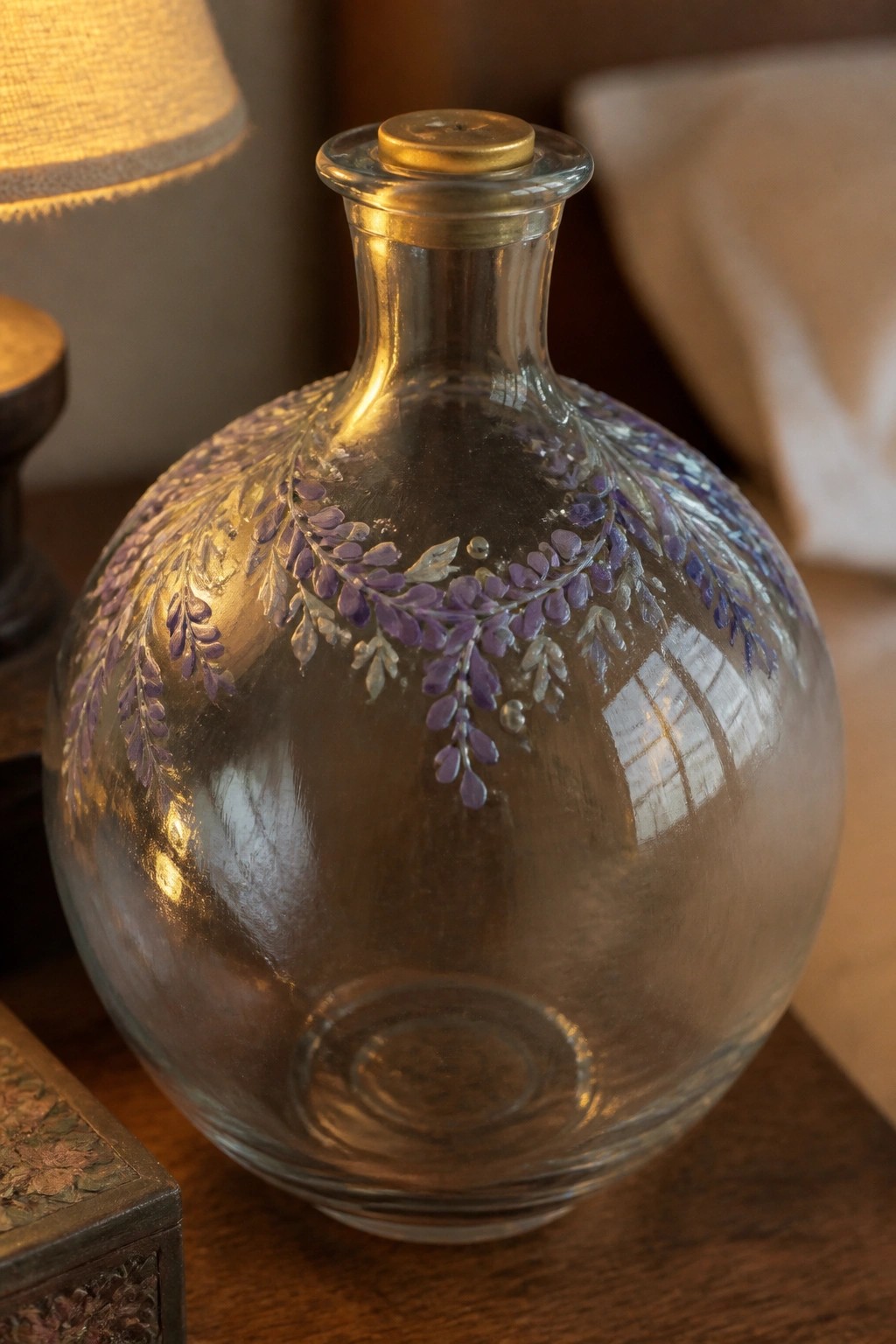 Glass bottle with purple floral design and gold cap on wooden table