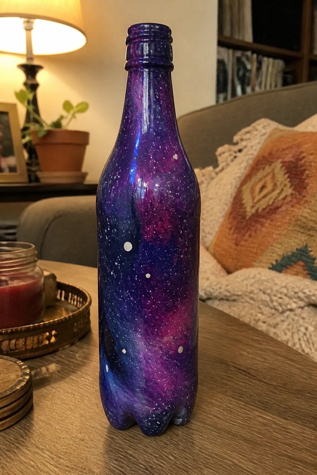 Colorful galaxy-painted bottle with purple blue swirls and white stars on wooden table