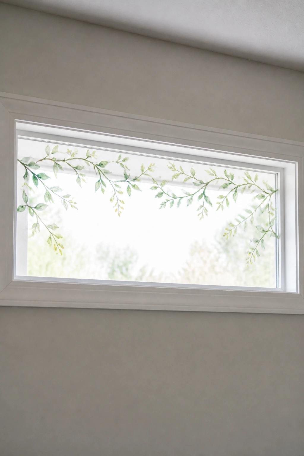 Rectangular window with white frame and green vine-patterned roller shade