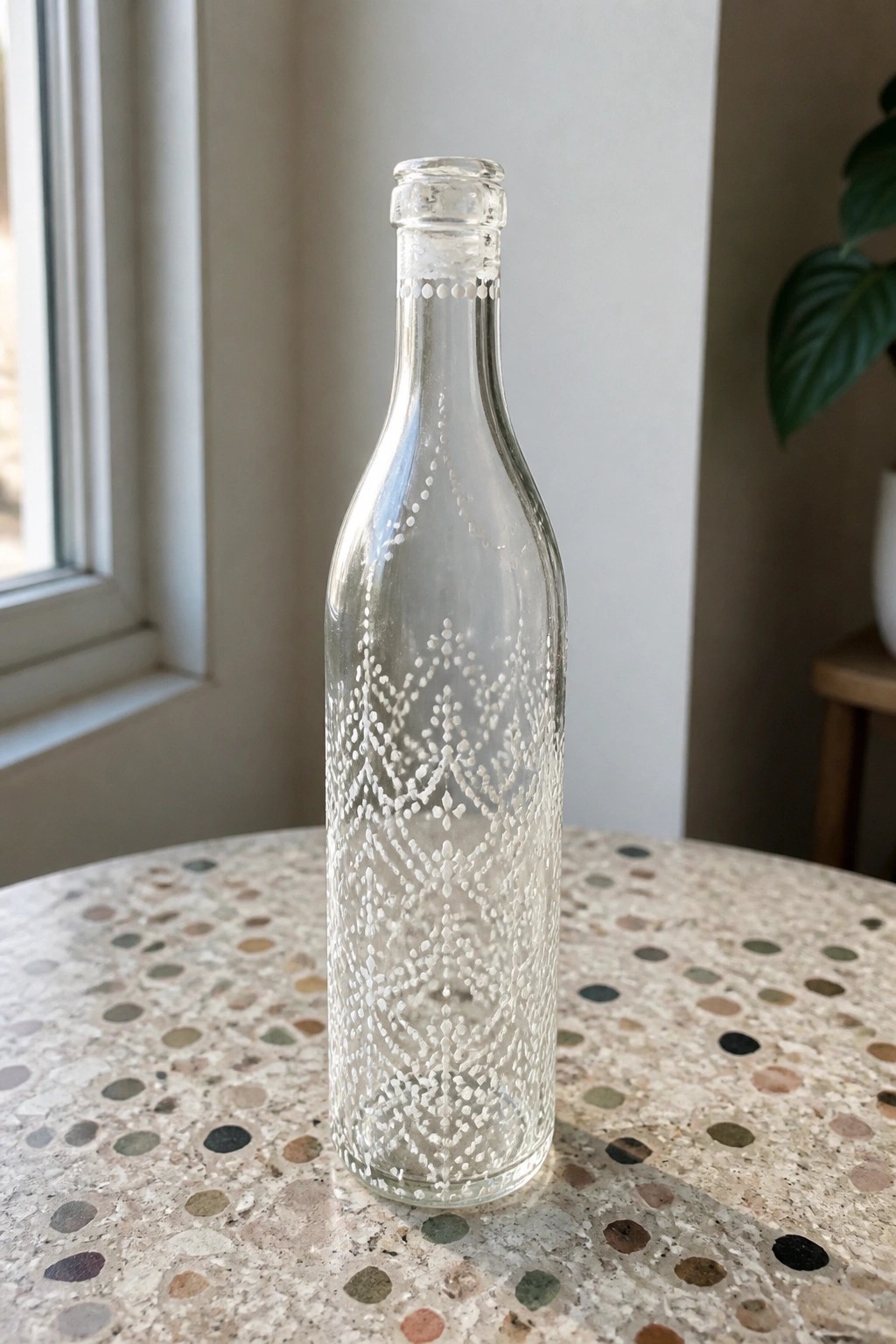 Clear glass bottle with white dotted patterns on speckled terrazzo countertop