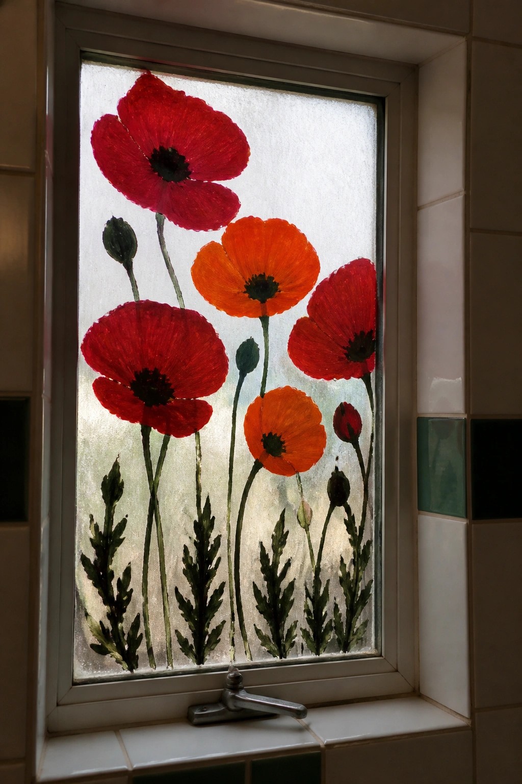 Red and orange poppies painted on frosted window above metal faucet.