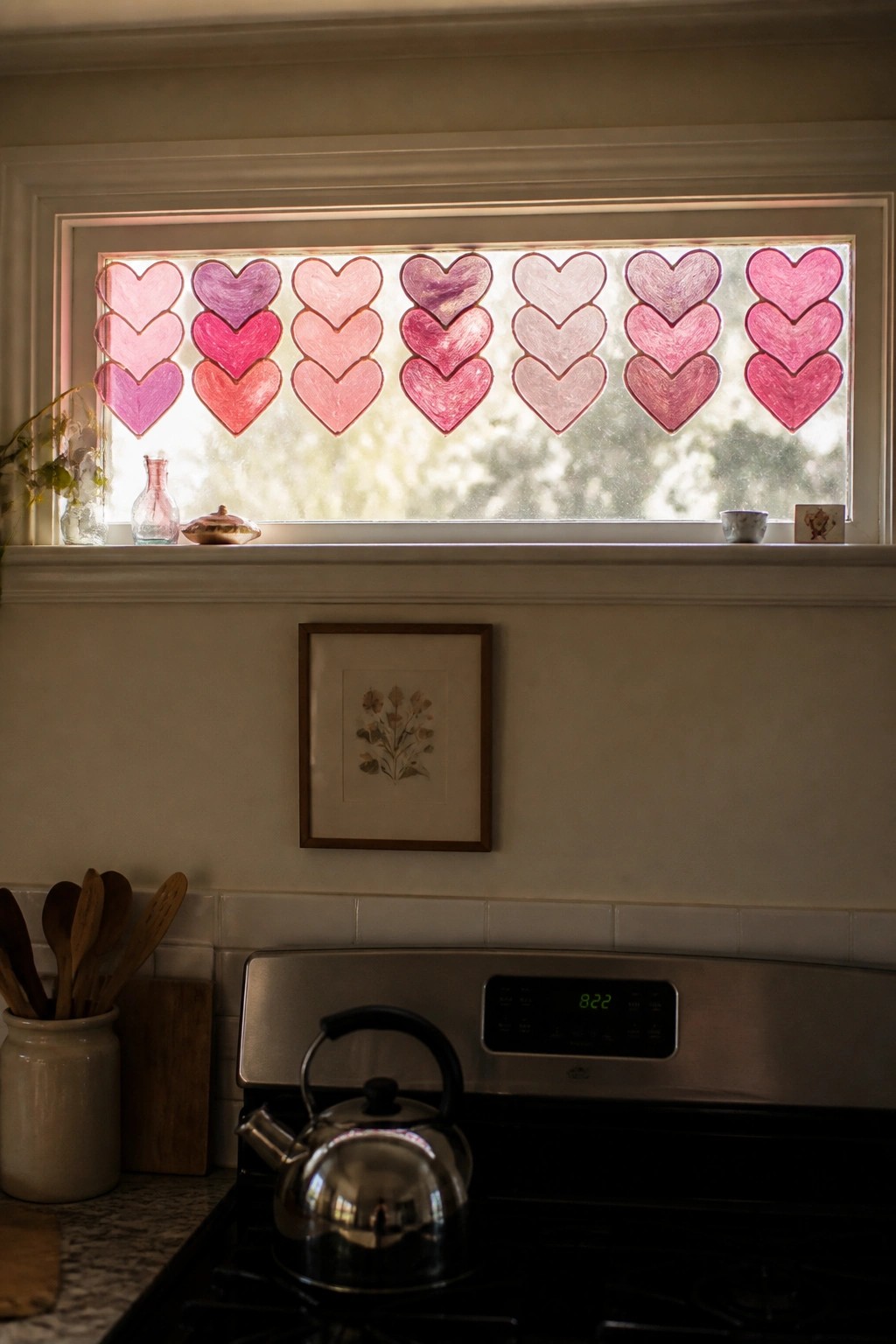 Kitchen window lined with rows of pink and purple paper hearts above stove with kettle