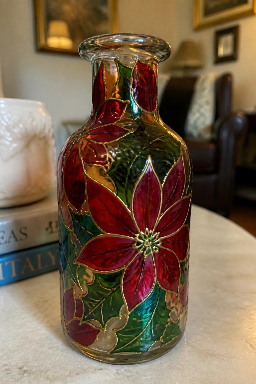 Glass bottle with red poinsettia flowers, green leaves, and gold outlines.