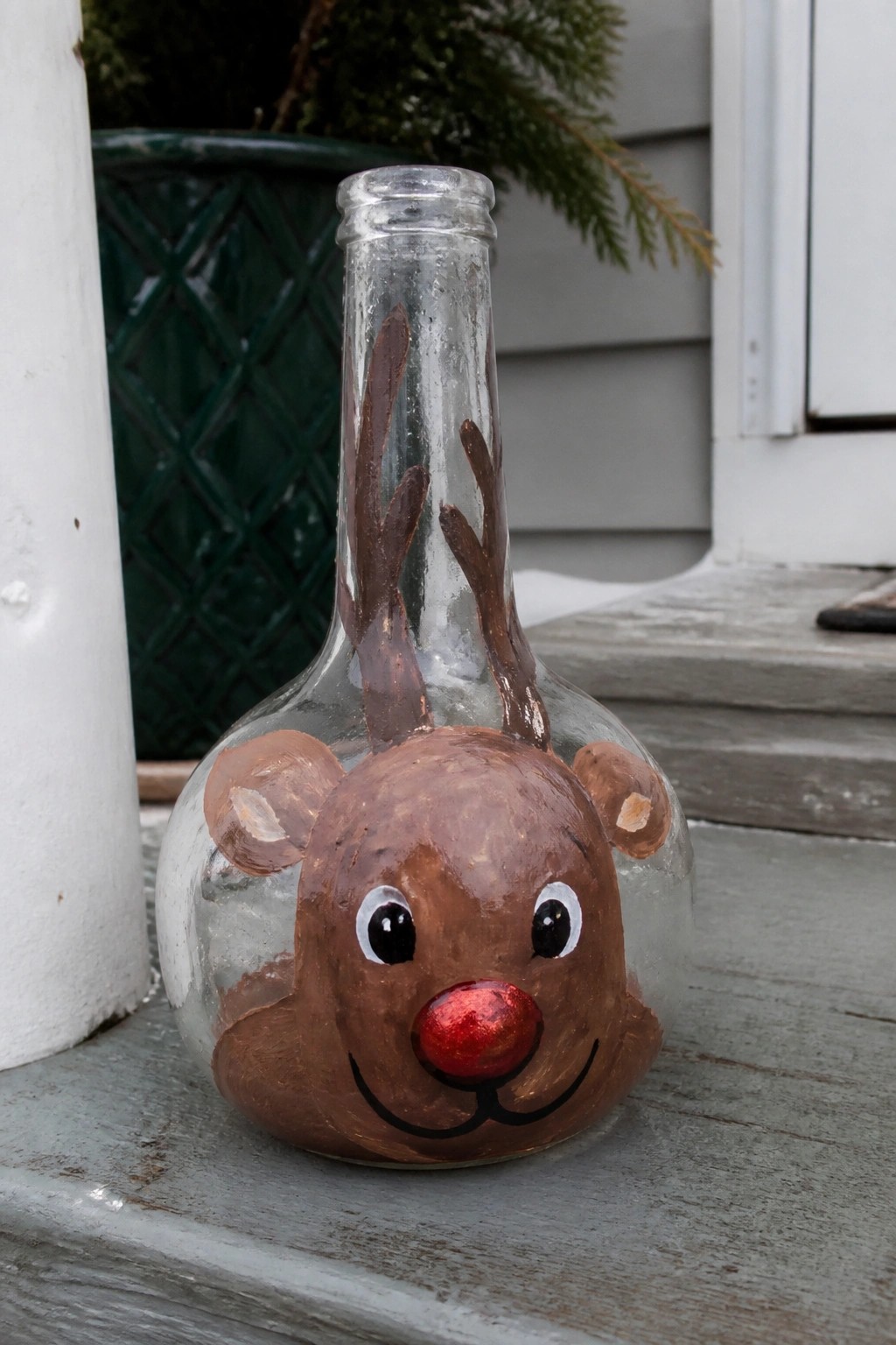 Painted glass bottle as reindeer with brown face, antlers, and shiny red nose