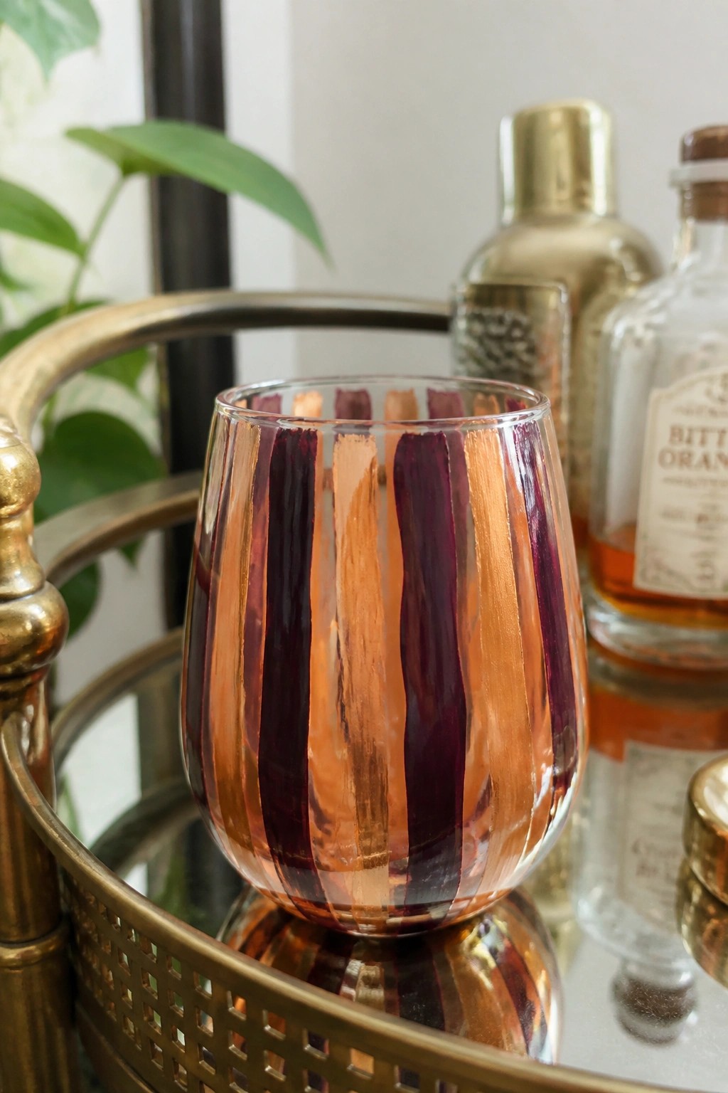 Purple and copper striped stemless glass on brass bar cart with bottles