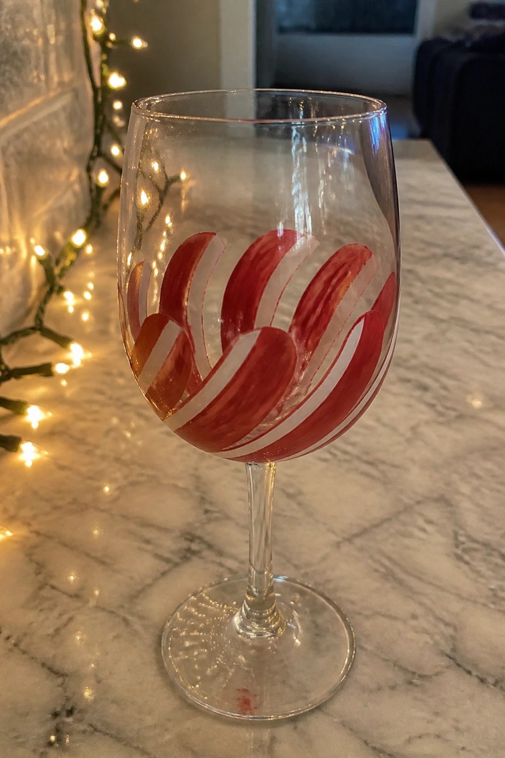Clear wine glass with red and white swirling stripes on marble countertop