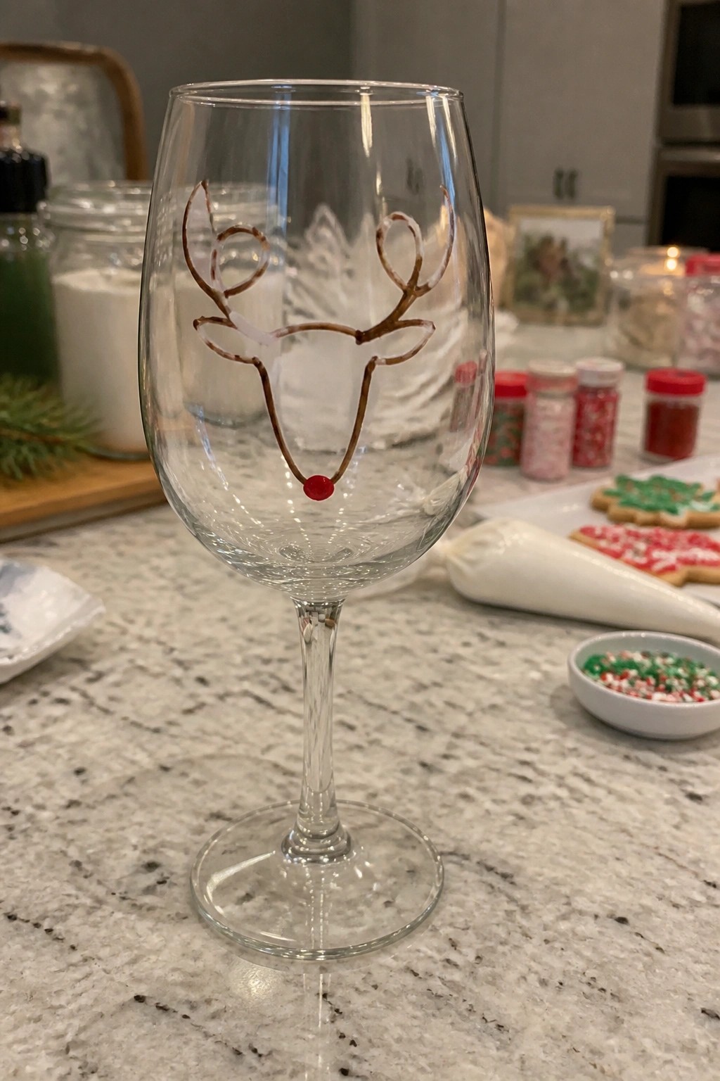 Clear wine glass with reindeer antlers and red nose on festive marble counter