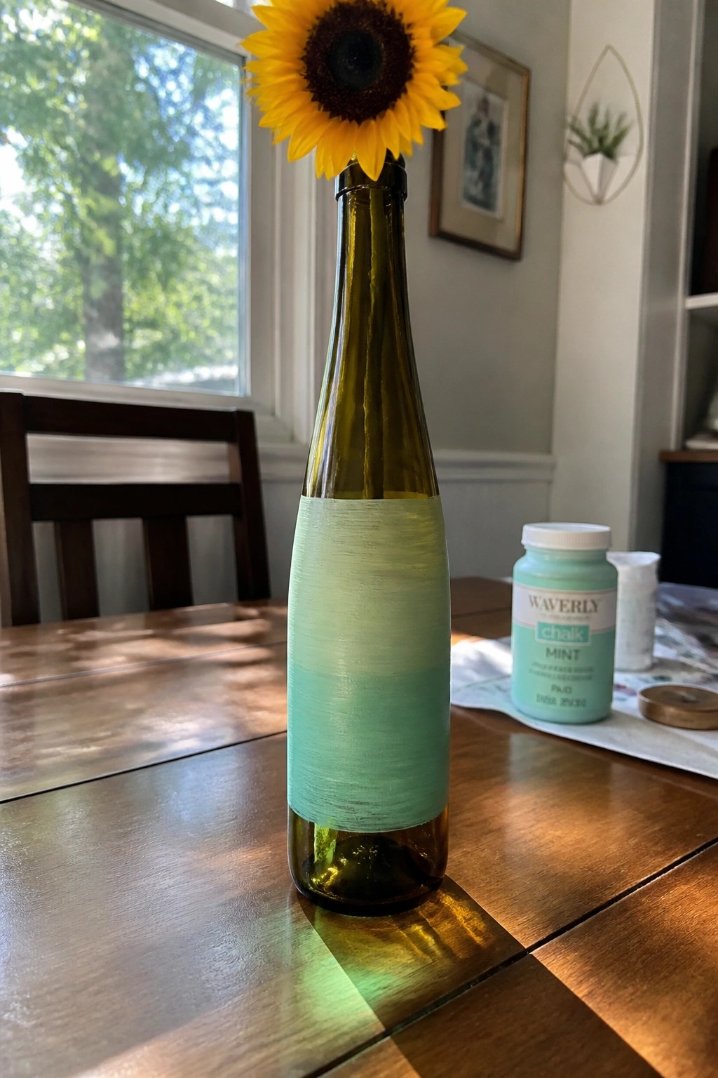 Sunflower in green bottle partially painted mint with chalk paint jar on wooden table